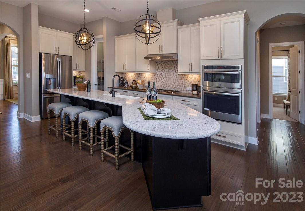 a kitchen with stainless steel appliances granite countertop a stove refrigerator and a dining table with wooden floor