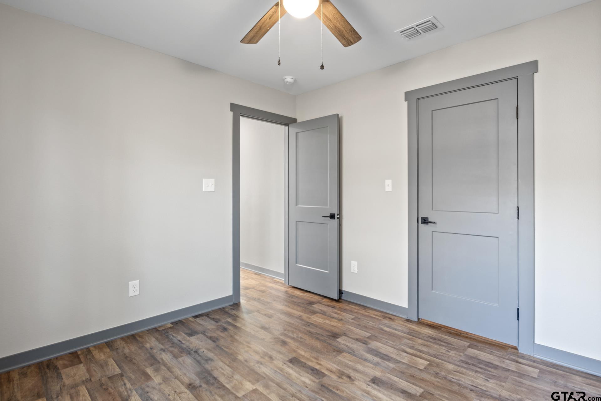 109 Yates Street Mount Vernon, TX 75457 - Photo 18 of 23 an empty room with wooden floor and a ceiling fan