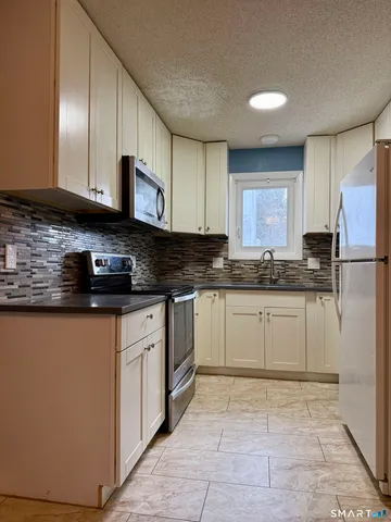 a kitchen with stainless steel appliances granite countertop a stove a sink a refrigerator a microwave and cabinets