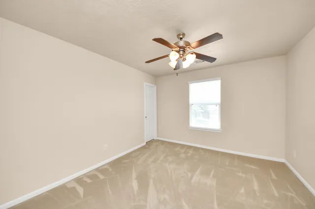 an empty room with a chandelier fan and closet