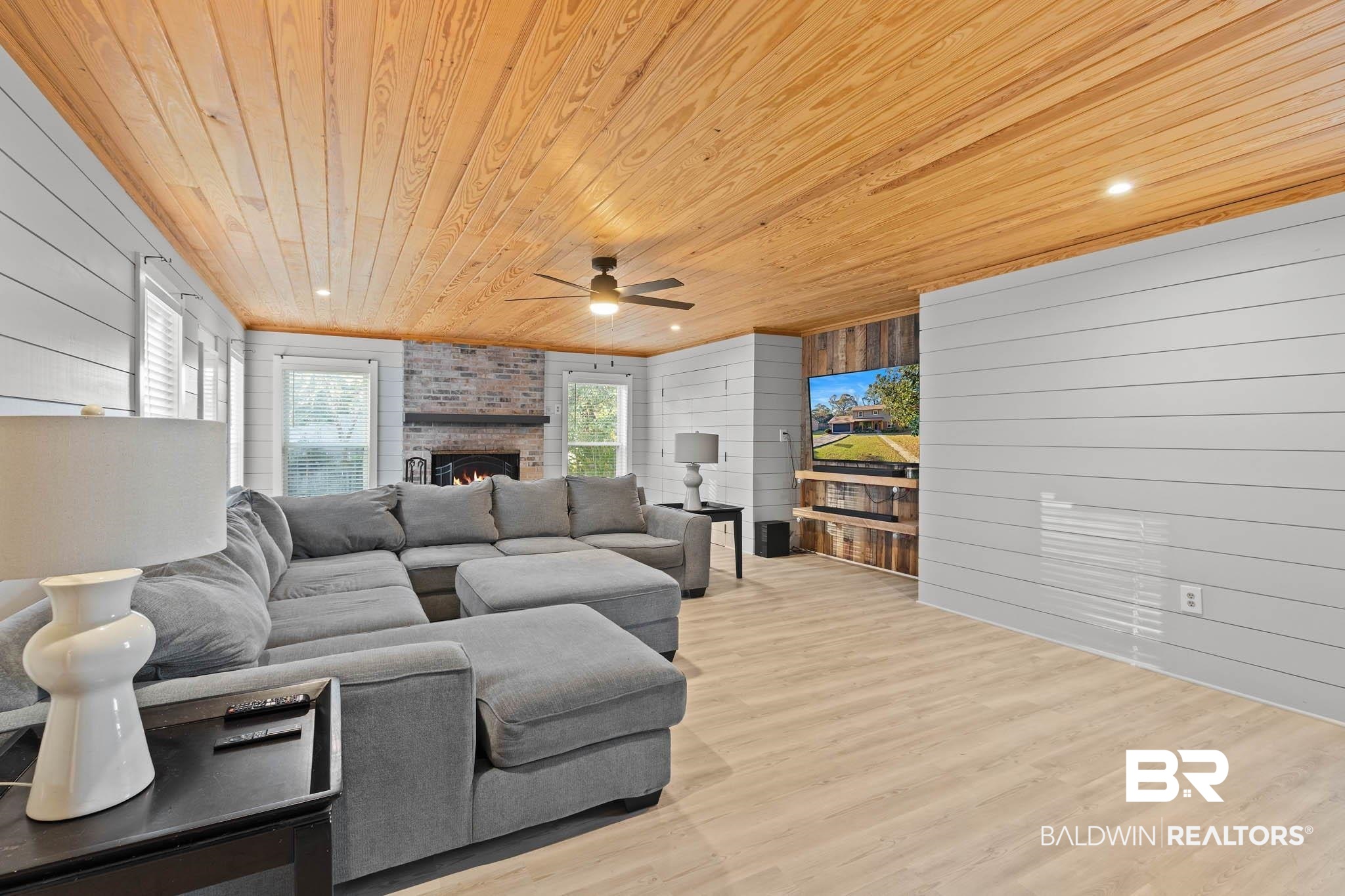 608 Southern Way Daphne, AL 36527 - Photo 12 of 35 Living room featuring wood walls, wood ceiling, light wood-type flooring, a ceiling fan, and a brick fireplace