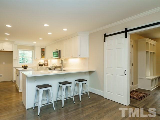 3317 Redbud Lane Raleigh, NC 27607 - Photo 9 of 25 a kitchen with kitchen island granite countertop wooden floors and chairs
