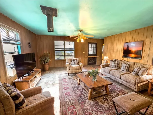 a living room with furniture a flat screen tv and a large window