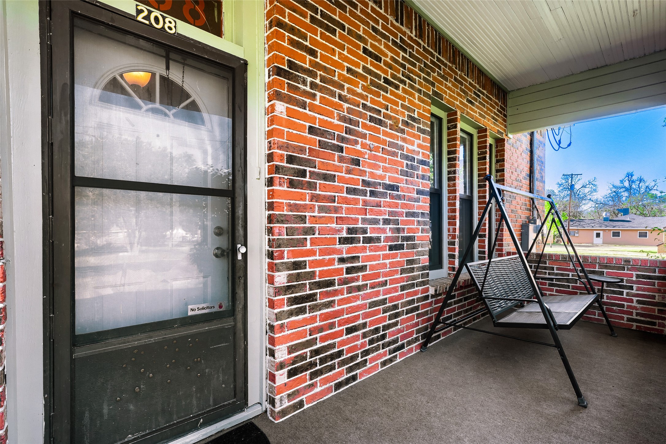 208 North Ave B Elgin, TX 78621 - Photo 3 of 29 Enjoy the front porch swing, perfect for relaxing. The entrance features a glass storm door, adding both style and functionality.