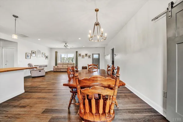 a dining room with wooden floor a chandelier a glass table and chairs