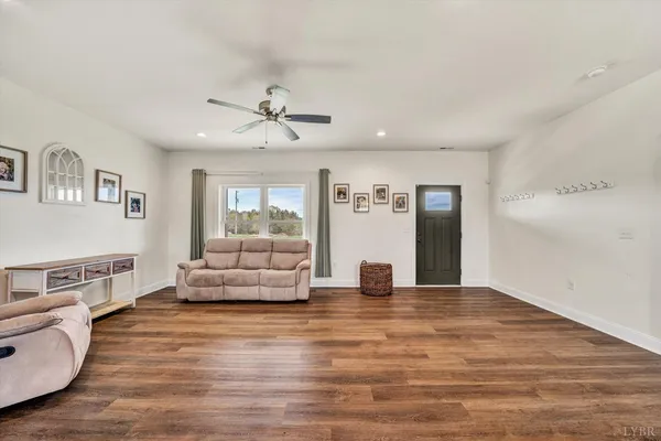 a view of an empty room with kitchen and window