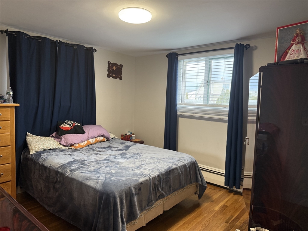 77 Roland Road Revere, MA 02151 - Photo 10 of 13 a bedroom with a bed and wooden floor