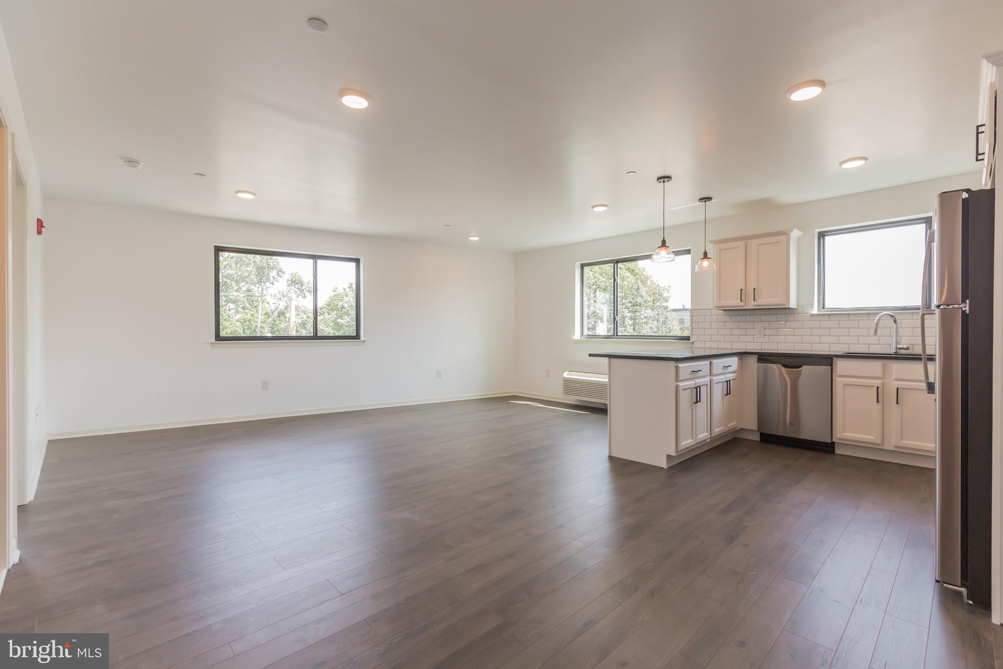 6778 Ridge Avenue, Unit 403 Philadelphia, PA 19128 - Photo 1 of 11 a large kitchen with stainless steel appliances granite countertop a stove a sink a refrigerator white cabinets and wooden floor
