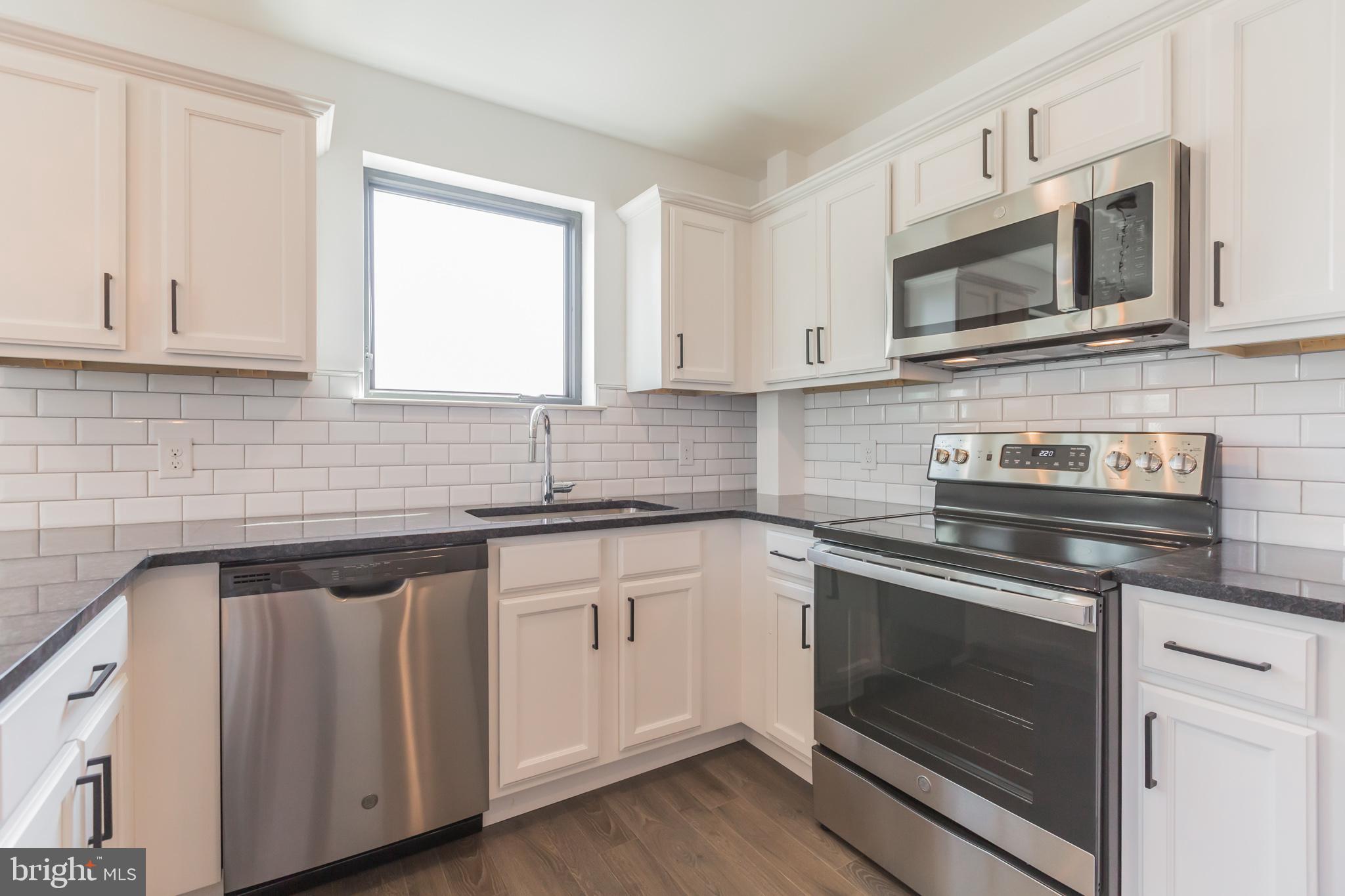 6778 Ridge Avenue, Unit 403 Philadelphia, PA 19128 - Photo 2 of 11 a kitchen with cabinets stainless steel appliances a sink and a microwave