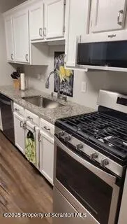 a kitchen with granite countertop a stove and a white cabinets