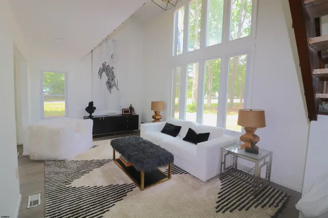 a living room with furniture a floor to ceiling window and a flat screen tv