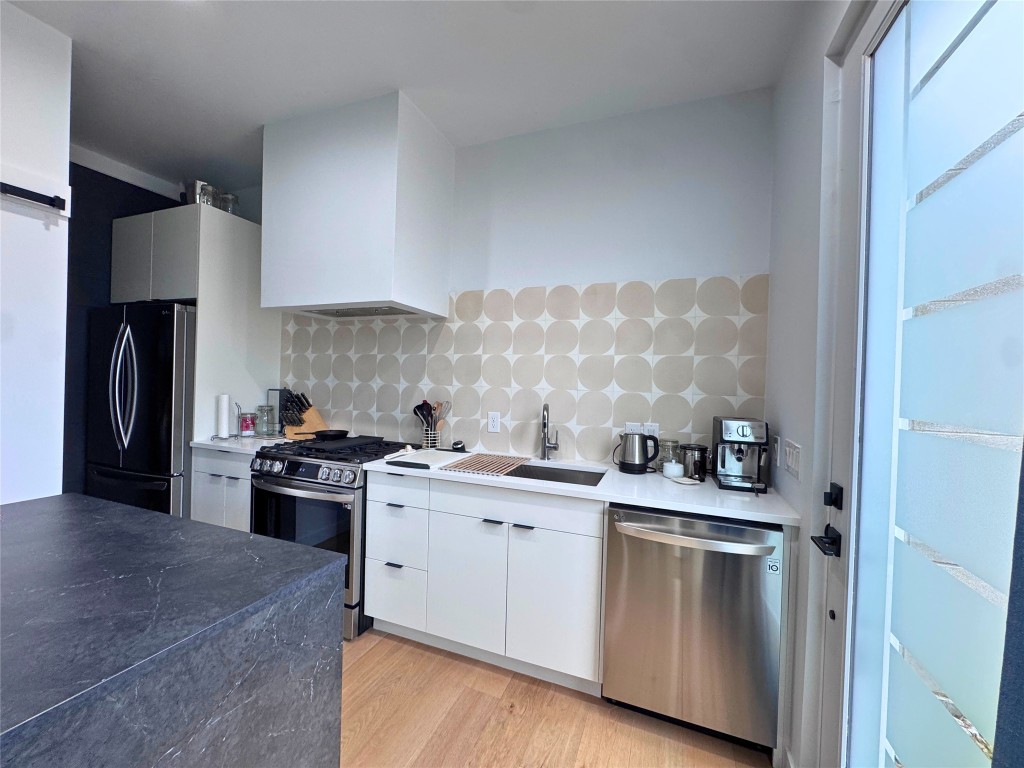 1206 Luna Street, Unit 2 Austin, TX 78721 - Photo 10 of 20 a kitchen with stainless steel appliances granite countertop a stove a sink and a refrigerator