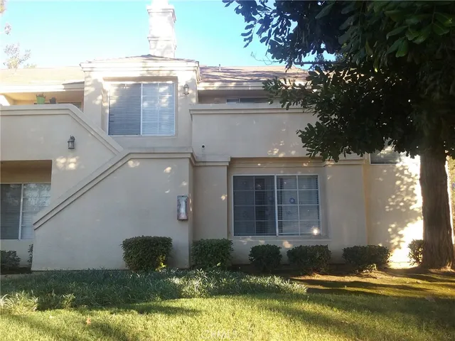 a view of a house with a yard and a large tree