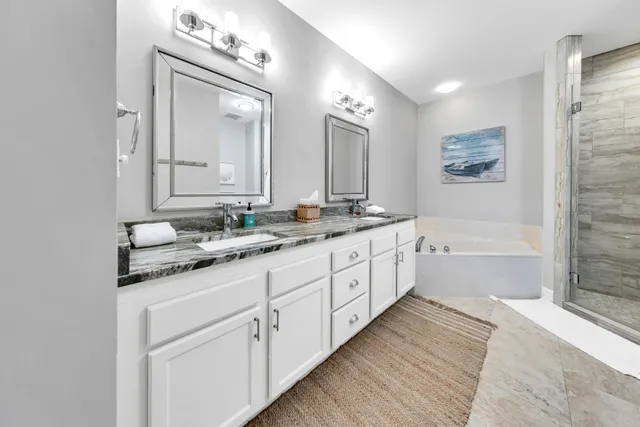 a bathroom with a granite countertop double vanity sink a mirror and a bathtub