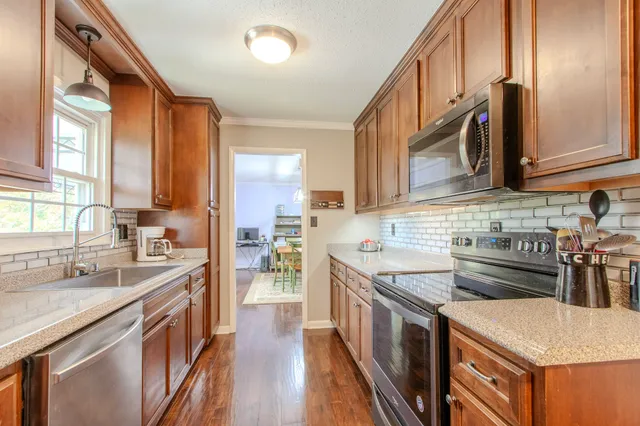 a kitchen with stainless steel appliances granite countertop a sink a stove and a refrigerator