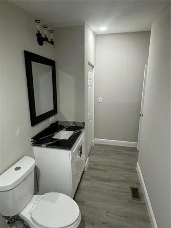 a bathroom with a granite countertop toilet sink and mirror