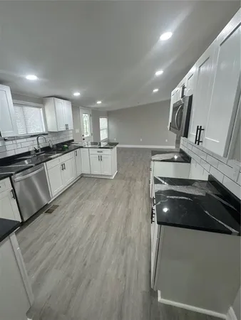 a kitchen with stainless steel appliances a sink a stove top oven a counter space and cabinets