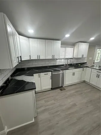 a kitchen with stainless steel appliances granite countertop a stove a sink and white cabinets