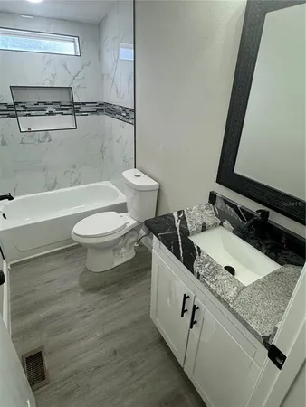 a bathroom with a granite countertop sink toilet and shower