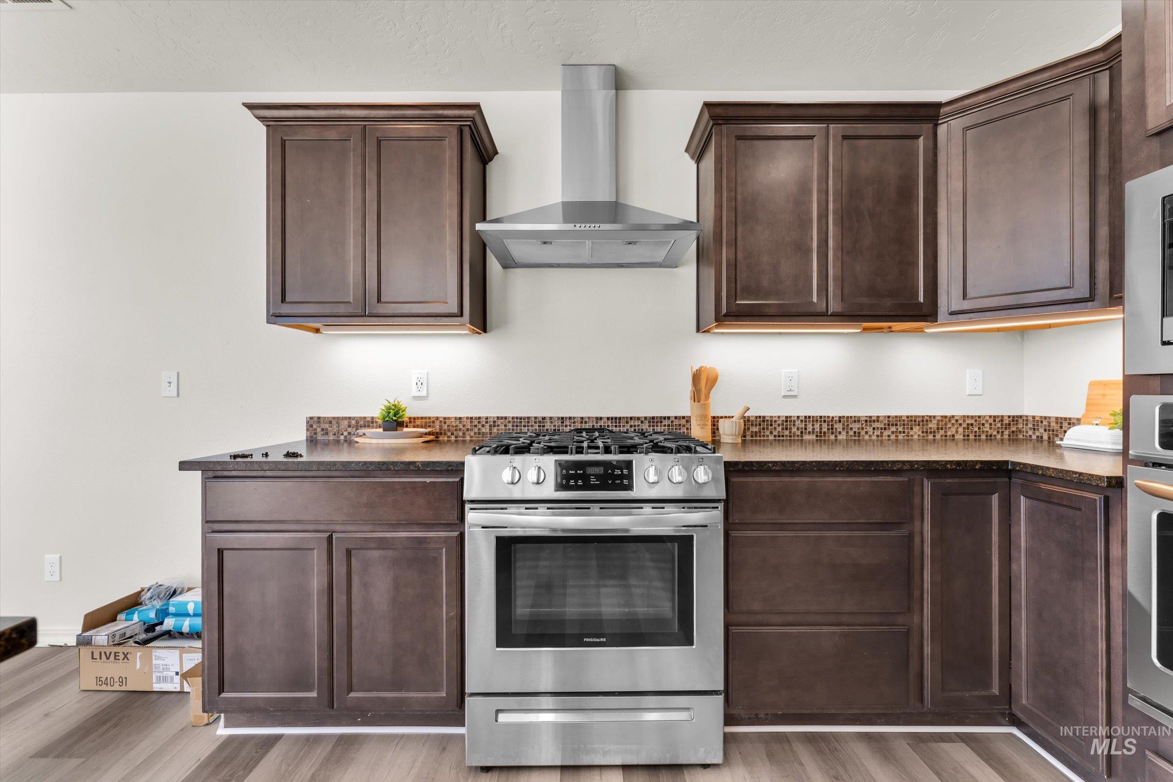 5602 Barkley Way Caldwell, ID 83607 - Photo 11 of 36 Kitchen with stainless steel appliances, dark wood finish cabinetry, light wood-type flooring, and dark stone counters