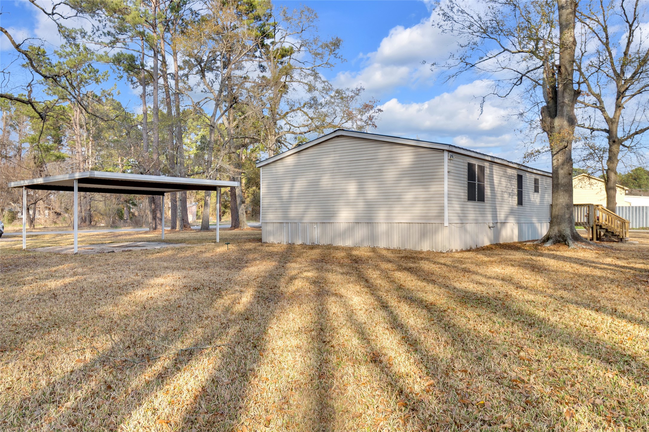 22094 Spear Road Porter, TX 77365 - Photo 5 of 45 This property features a spacious mobile home with a well-maintained yard, mature trees, and a covered parking area. The home is positioned in a peaceful, natural setting, ideal for those seeking a quiet lifestyle.