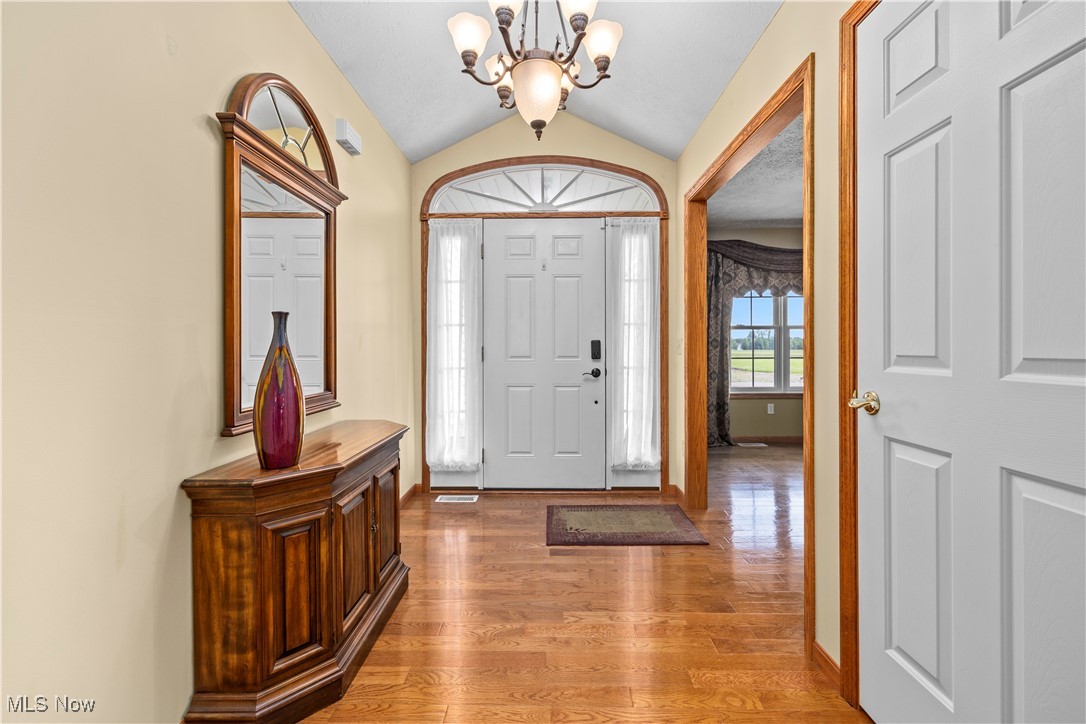 47147 Merriam Road Wellington, OH 44090 - Photo 38 of 49 Front entryway with a chandelier, vaulted ceiling, and light wood-style flooring