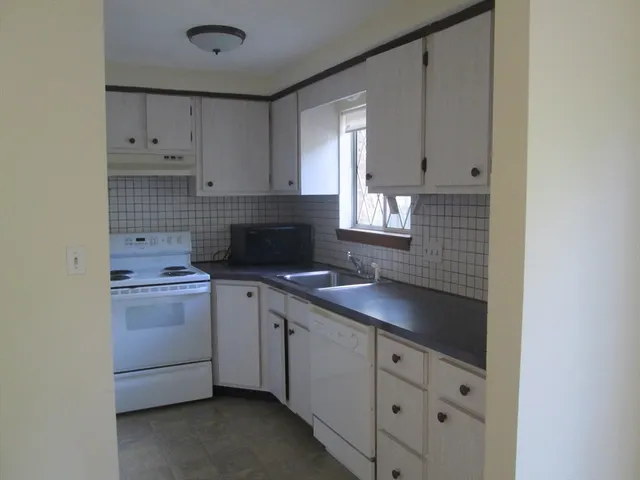 a kitchen with cabinets appliances a sink and a window