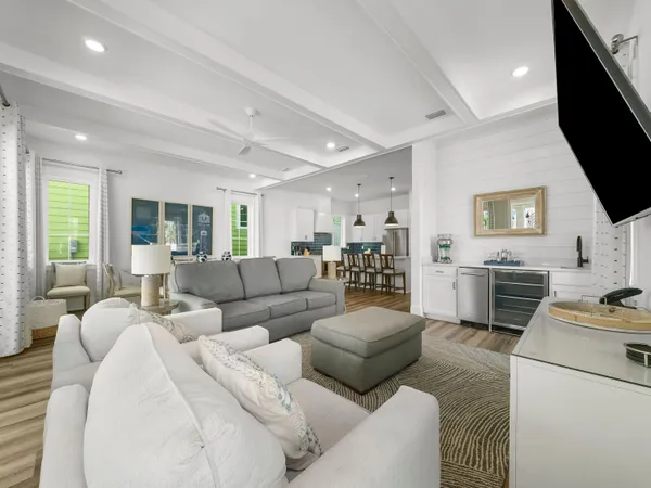 a living room with furniture a flat screen tv and a refrigerator
