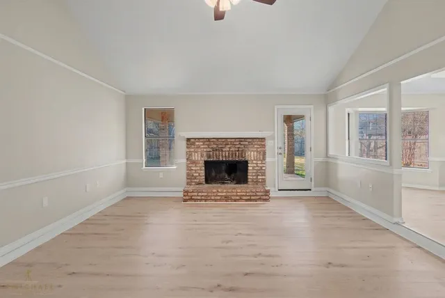 an empty room with windows and fireplace