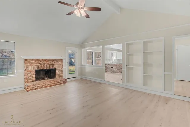 a view of an empty room with a fireplace and a window