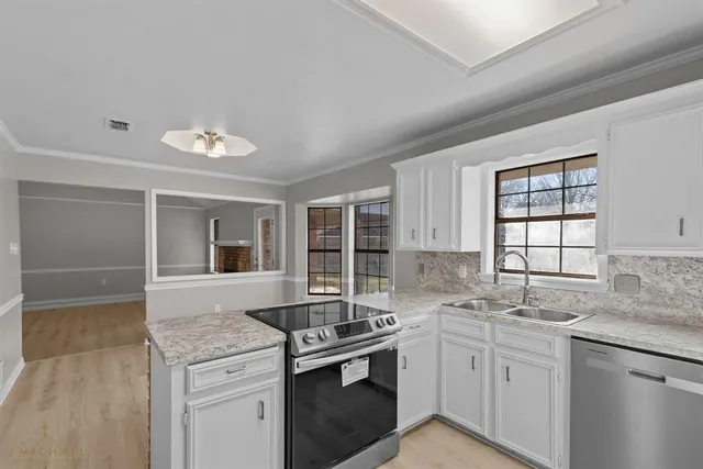 a kitchen with granite countertop a sink stainless steel appliances and cabinets