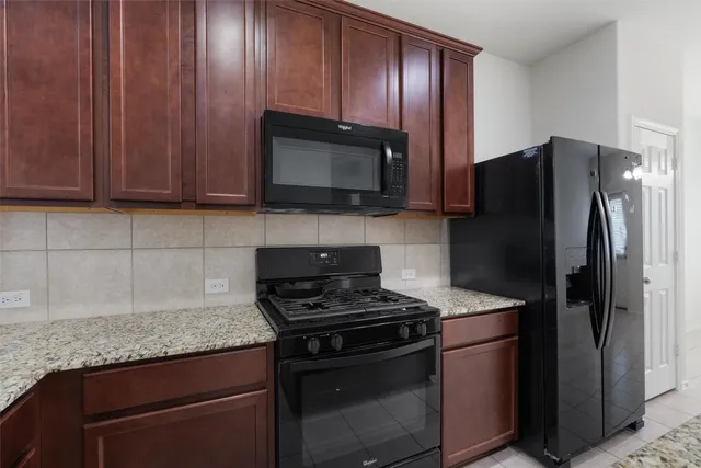 a kitchen with granite countertop wooden cabinets and stainless steel appliances