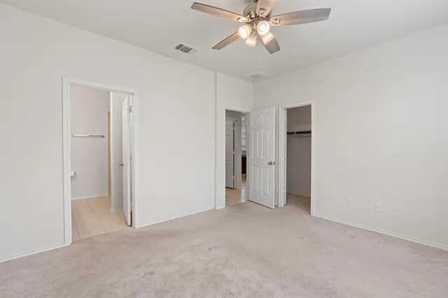 a view of an empty room and chandelier fan