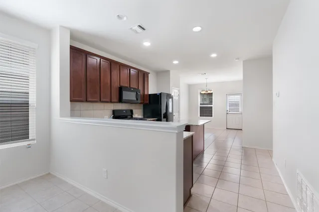 a kitchen with kitchen island granite countertop a sink dishwasher stove top oven and wooden cabinets