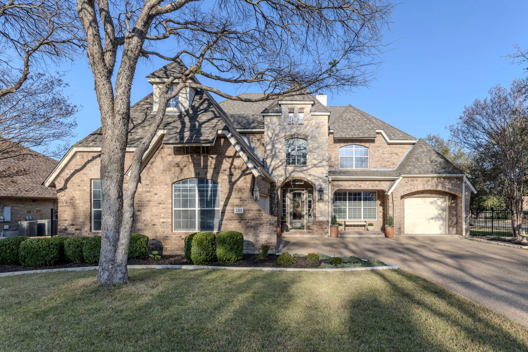 View of front facade featuring brick siding, a garage, asphalt driveway, and covered porch