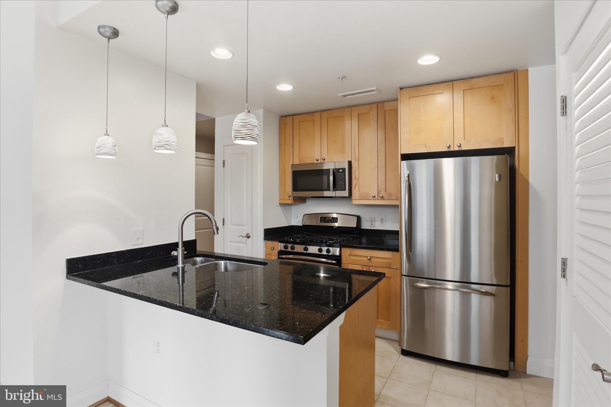 11990 Market Street, Unit 216 Reston, VA 20190 - Photo 19 of 41 a kitchen with stainless steel appliances granite countertop a refrigerator a sink a stove and a refrigerator with wooden floor