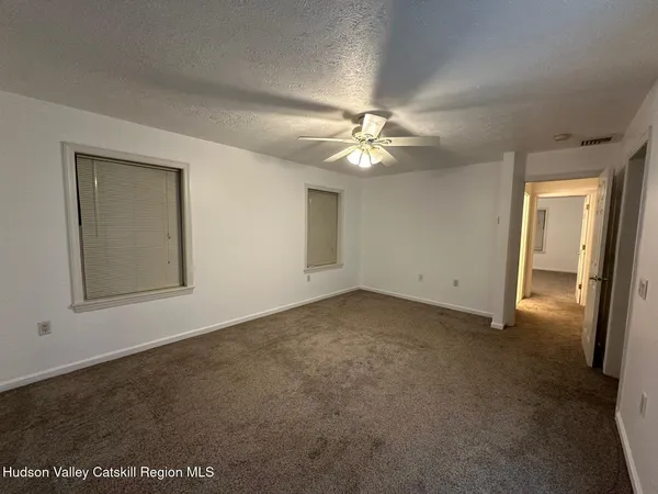 an empty room with a chandelier fan and windows