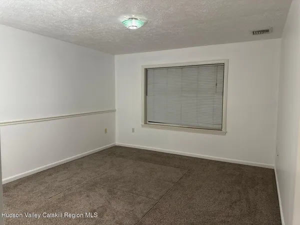 an empty room with a fan & a window