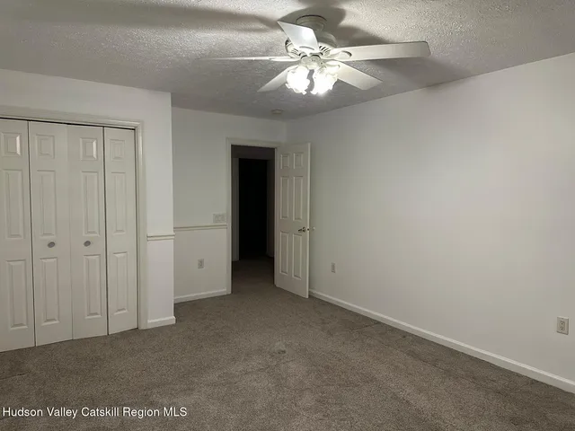 an empty room with chandelier fan and windows