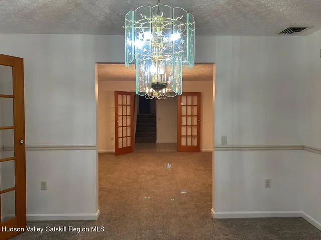an empty room with chandelier fan and windows