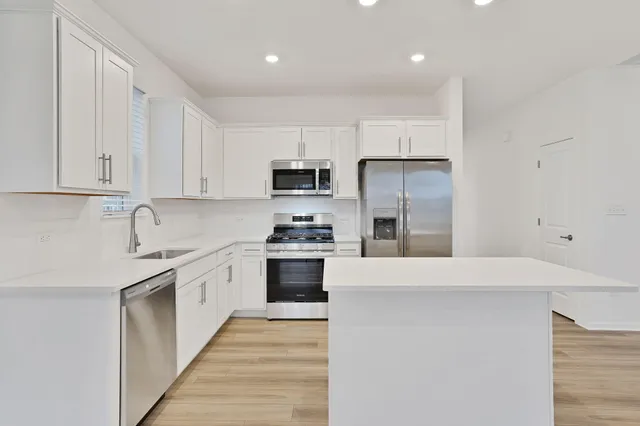 a kitchen with kitchen island granite countertop white cabinets and stainless steel appliances