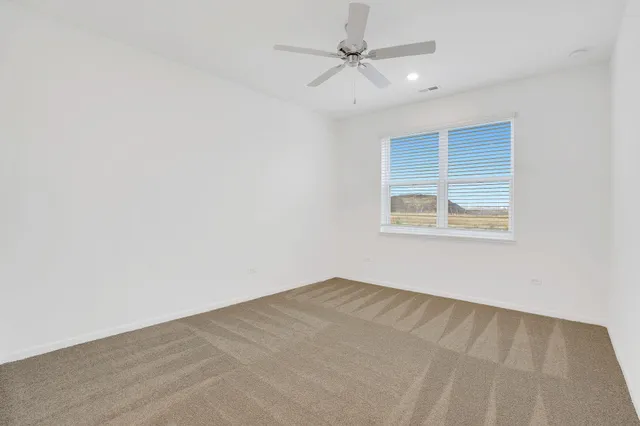 an empty room with a window and ceiling fan