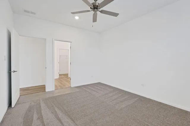 an empty room with a ceiling fan and carpet