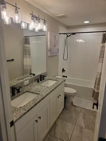 a bathroom with a granite countertop sink a toilet and shower