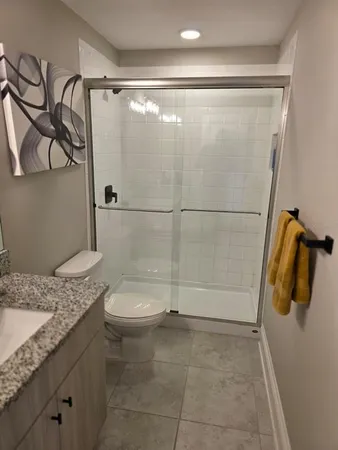 a bathroom with a granite countertop sink a toilet and shower
