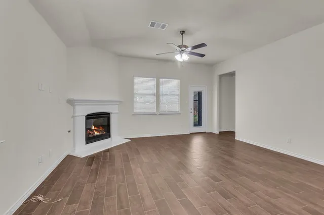 an empty room with windows fireplace and fan
