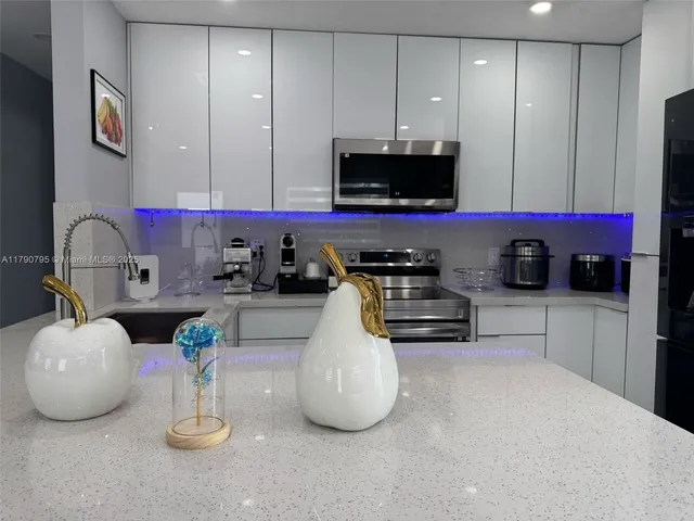 a kitchen with kitchen island granite countertop a sink a stove and a microwave