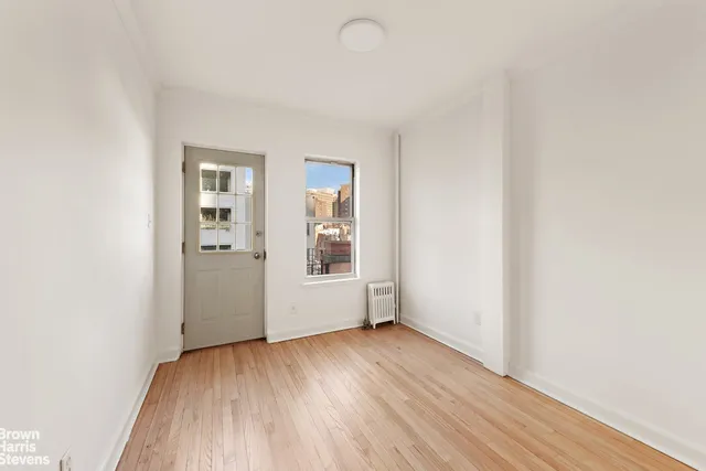 a view of an empty room with wooden floor and stairs