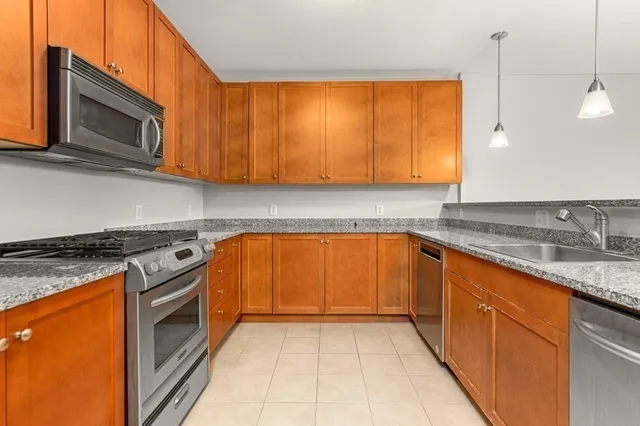 a kitchen with stainless steel appliances granite countertop a stove a sink and a microwave
