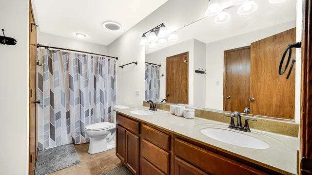a bathroom with a double vanity sink toilet mirror and shower